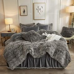 a bed covered in grey fur and pillows