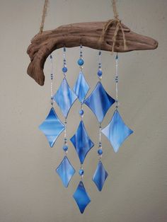 a wind chime hanging from a tree branch with blue glass tiles and beads on it