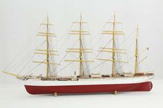 a red and white model ship on a white surface with no people in the photo