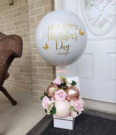 a large balloon sitting on top of a white box filled with pink and gold flowers