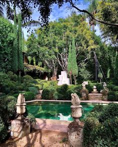 an outdoor pool surrounded by greenery and stone pillars in the middle of a garden