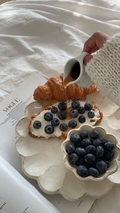 a person pouring blueberries into a bowl on top of a white flower shaped plate