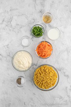 the ingredients to make macaroni and cheese are shown in bowls on a marble surface