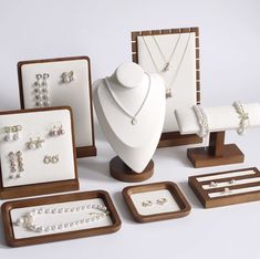 an assortment of jewelry displayed on wooden stands and trays with necklaces, bracelets, earrings, and rings