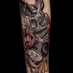 a tattoo with an animal on it's arm and flowers in the back ground