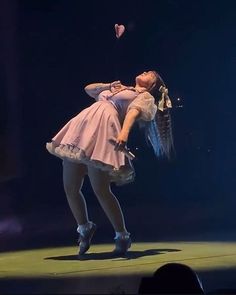 a woman is performing on stage with her hands behind her back and feet in the air