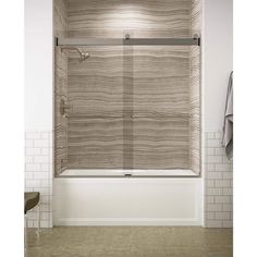 a bathroom with white tile walls and a bathtub in the center, along with two towels hanging on the wall