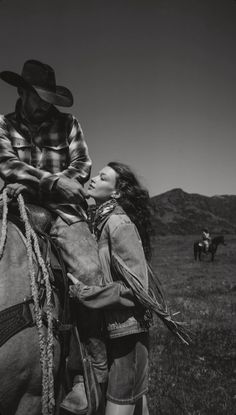 black and white photograph of a woman kissing a man on the back of a horse