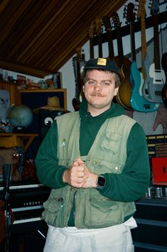 a man in green shirt and white shorts standing next to guitar strings hanging on the wall