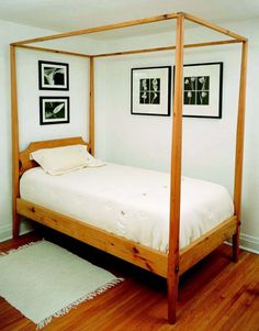 a four poster bed in a white bedroom with wood floors and pictures on the wall