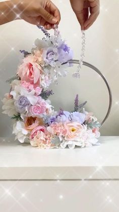 a person is placing flowers on the top of a flower wreath with beaded hands