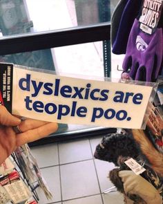 a person holding up a sign that says dyslexics are people poo