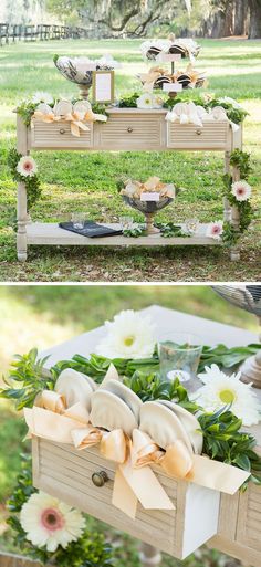 a table with flowers and plates on it in the middle of grass, next to a wooden