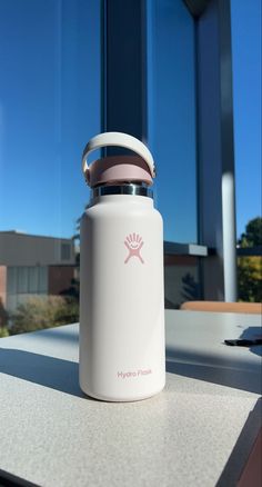 a white water bottle sitting on top of a table next to a large glass window