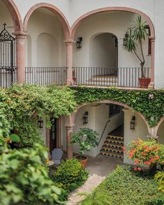 an outdoor courtyard with potted plants and steps leading up to the second floor balcony