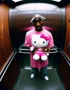 a man holding a hello kitty stuffed animal in his arms while standing next to an elevator