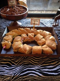 an assortment of sandwiches on display in a box with zebra print tablecloth and other food items