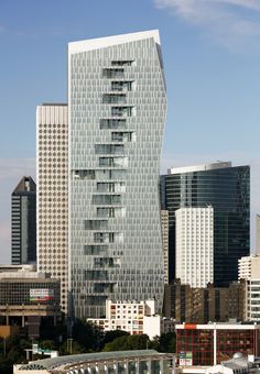 a very tall building with lots of windows in front of some other buildings and water