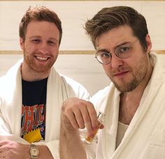 two men in bathrobes are smiling and holding something