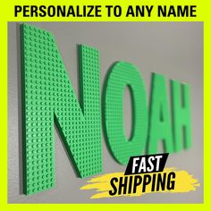 the word noh is spelled in green lego letters on a gray wall with yellow lettering