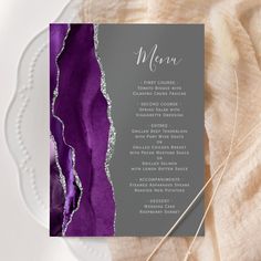 a purple and silver wedding menu on a plate