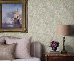 a painting hangs on the wall next to a bed with pillows and a vase filled with flowers