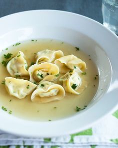 a white bowl filled with dumplings on top of a green and white table cloth