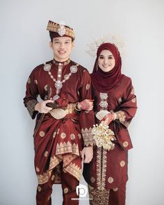 two people dressed in red and gold standing next to each other