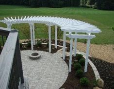 a white pergolated area with benches and trees in the background