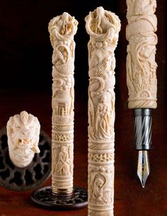 three carved ivory candles on a table with a pen and inkwell in the background