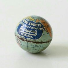 an old blue and orange globe with words on it sitting on a white table top