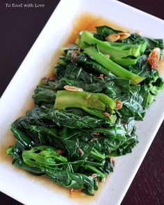 a white plate topped with greens covered in sauce