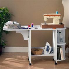 a sewing machine sitting on top of a white table next to a potted plant