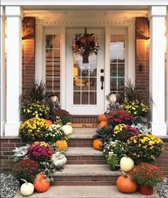 front porch decorated for fall with pumpkins, mumbers and other autumn flowers on the steps