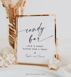 a candy bar sign sitting on top of a table next to some seashells