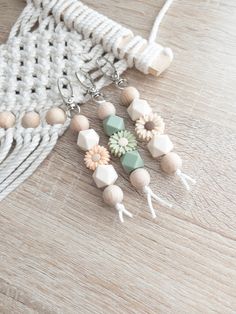 the earrings are made from wooden beads and tassels with flowers on them, along with a white crochet bag