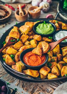 a platter filled with potatoes and guacamole dips on a table