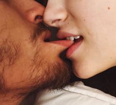 a man and woman kissing each other with their noses close to one another as they look into the camera