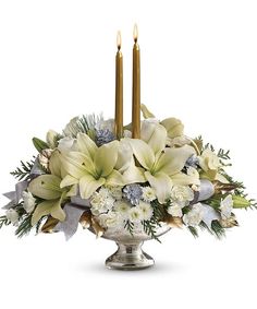 a white centerpiece with two candles and flowers