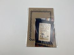 a cross - stitch kit in the package is displayed on a white surface with black and white checkered border