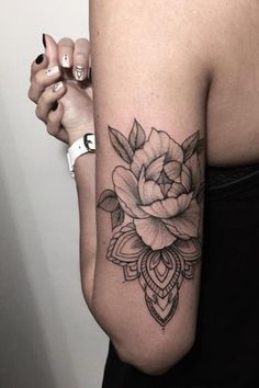 a woman's arm with a rose tattoo on the left side of her arm