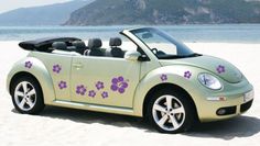 a convertible car with flowers painted on it's side sitting in the sand at the beach