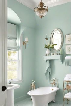 a white bath tub sitting next to a bathroom sink under a mirror and light blue walls