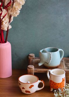 two mugs and a vase with flowers in them