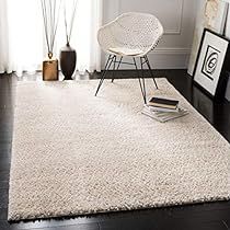 a white rug in a living room next to a chair and pictures on the wall