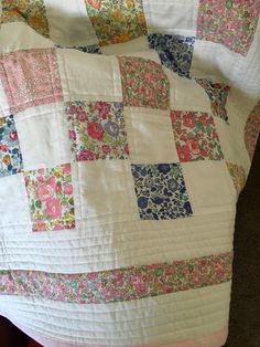 a white quilt with colorful patchwork on it sitting on top of a bed next to a pillow