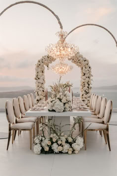 a table with white flowers and chairs around it is set up for a formal dinner