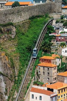 an aerial view of a train going down the tracks next to some buildings and trees