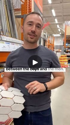 a man is standing in a store holding some tiles and pointing to the camera with his finger