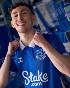 a young man in a blue shirt is posing for the camera with his fist up